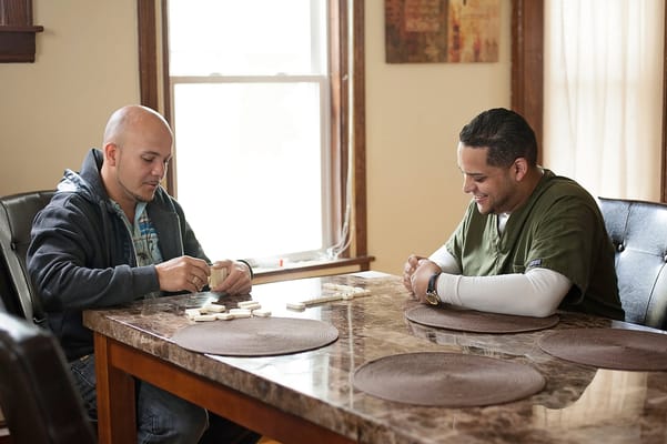 Two men playing dominoes at a table