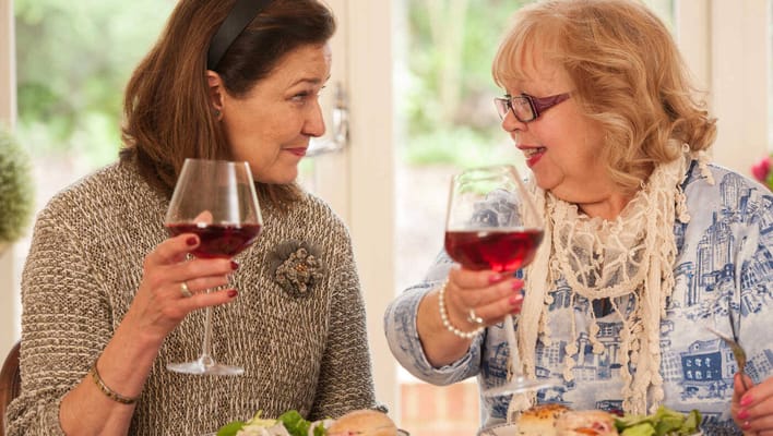 Two residents toasting with drinks at a table