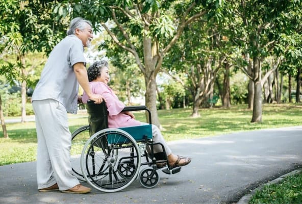 A caregiver assisting a resident in a park