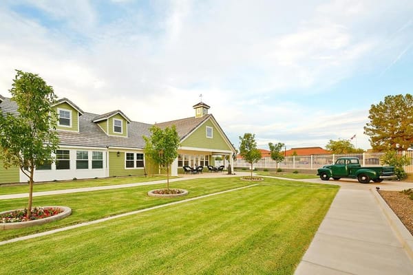 Exterior view of a senior living facility with a garden and vintage truck