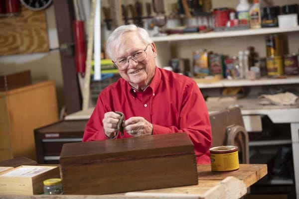 An elderly man working in a workshop, smiling