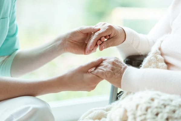 Close-up of caregiver holding elderly person's hands
