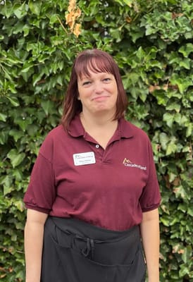 Staff member outside in front of greenery