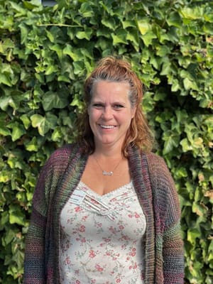 Staff member in front of a lush green wall