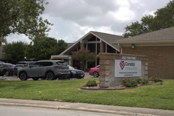 Exterior view of Caraday of Corpus Christi Assisted Living facility with cars parked in front.
