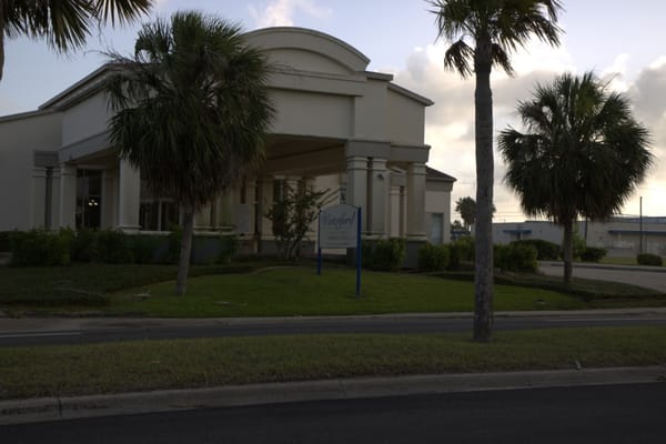 Exterior view of The Waterford senior living facility with palm trees