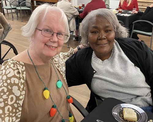 Two residents smiling together at a dining table