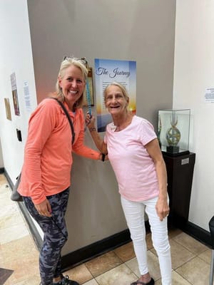 Two women smiling near a poster in the facility