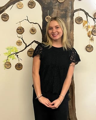 Staff member posing in front of an activity wall