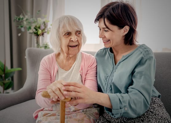 A caregiver smiling with a senior resident in a cozy interior