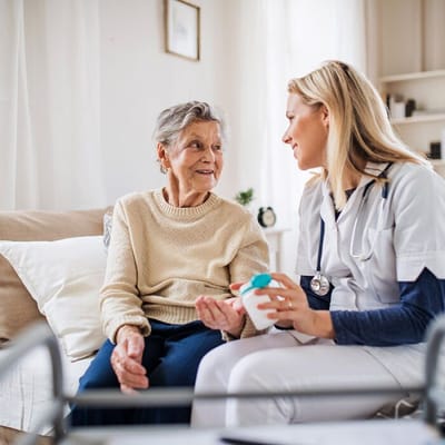 A nurse engaging with a smiling elderly resident in a cozy room