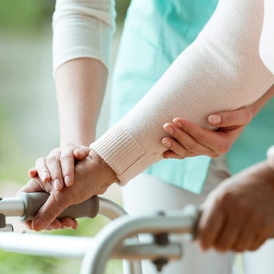 Caregiver assisting a resident with a walker outdoors