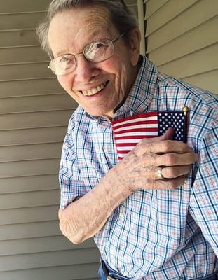 Senior resident smiling while holding a small American flag