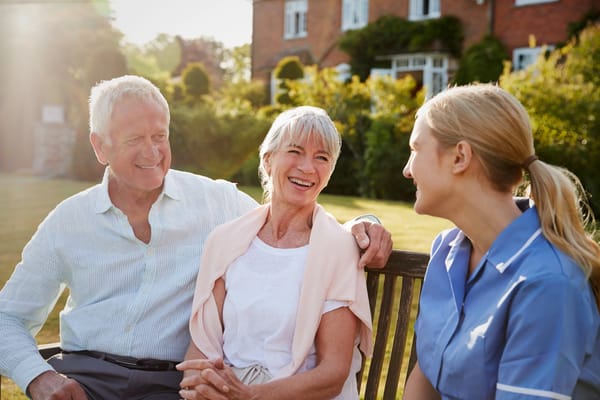 Residents and staff enjoying time outdoors on a bench