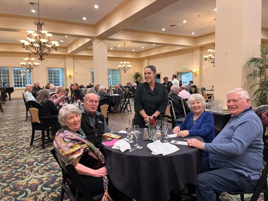 Residents enjoying dinner in a dining room with a staff member