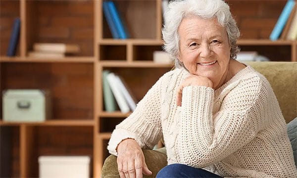 A smiling senior woman sitting in a cozy room
