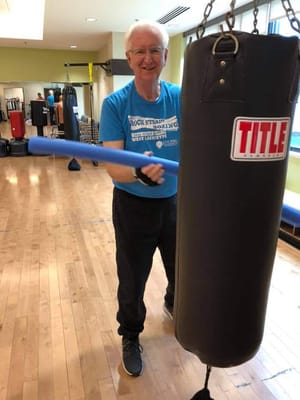 Senior resident engaging in boxing activity with a punching bag