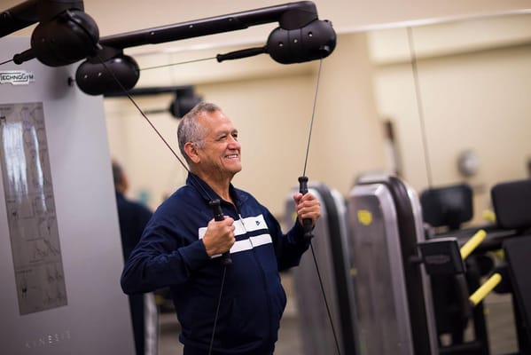 Senior exercising with gym equipment in a fitness room