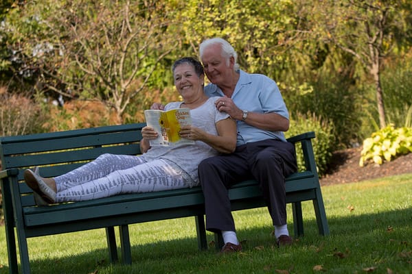 A couple enjoying a book on a bench in a garden