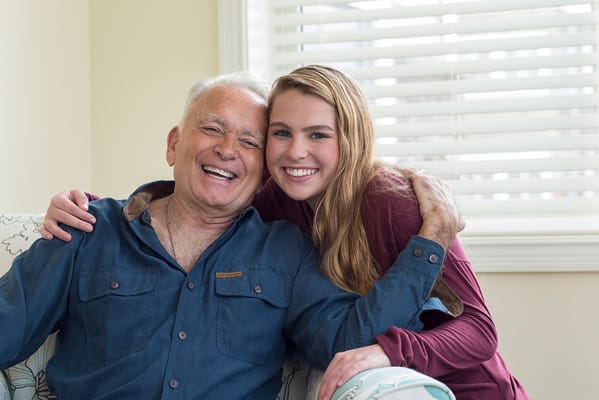 Elderly man and young woman smiling together indoors