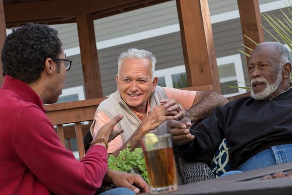 Three residents engaged in conversation on a patio