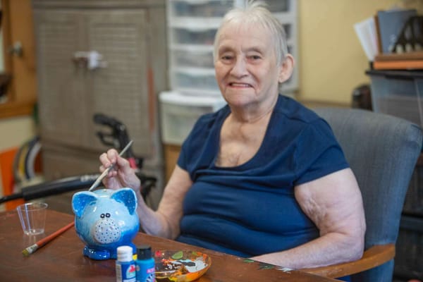 Resident painting a piggy bank in an activity room