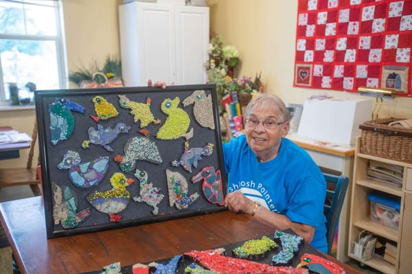 Resident displaying crafted artwork in an activity room