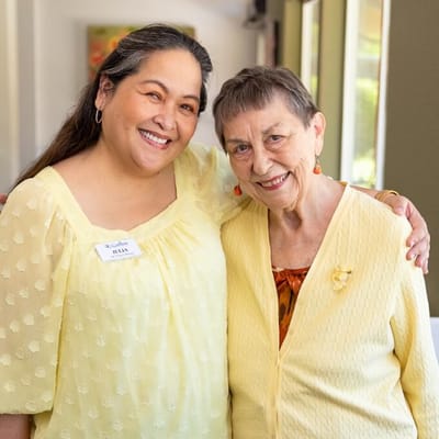 Staff member posing with a resident in a bright common area