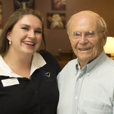 A staff member and resident smiling in a communal area