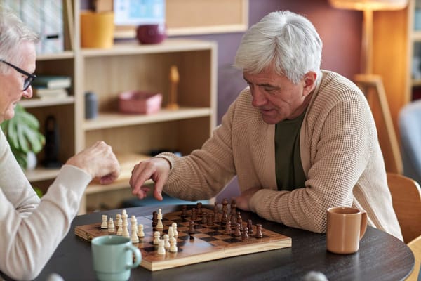 Two seniors playing chess in a cozy indoor setting