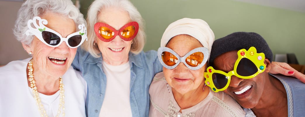 Four residents smiling and wearing fun oversized sunglasses