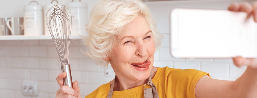 Senior woman playfully taking a selfie in the kitchen