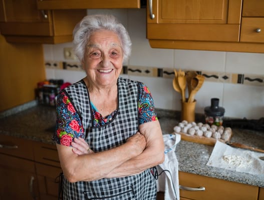 Smiling elderly woman baking in a kitchen