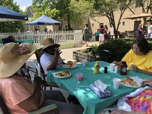 Residents enjoying a meal outdoors with plates and drinks
