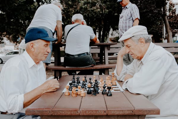 Two elderly men playing chess at an outdoor table