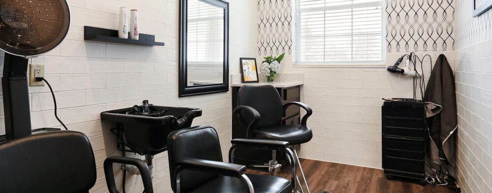 A hair salon area with styling chairs and a mirror