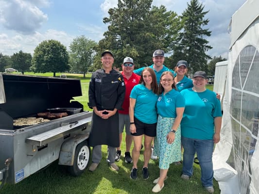 Staff posing with a grill at an outdoor event