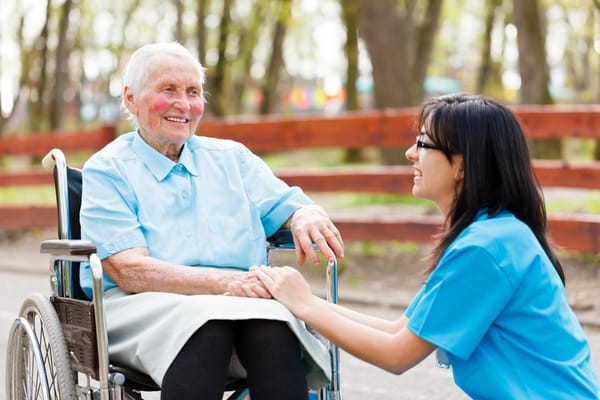A caregiver interacting with a smiling resident outdoors