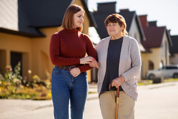A caregiver assisting a senior woman outdoors