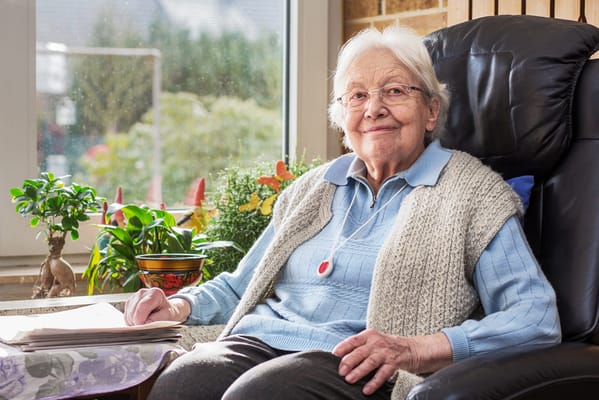 An elderly woman in a cozy chair by a window