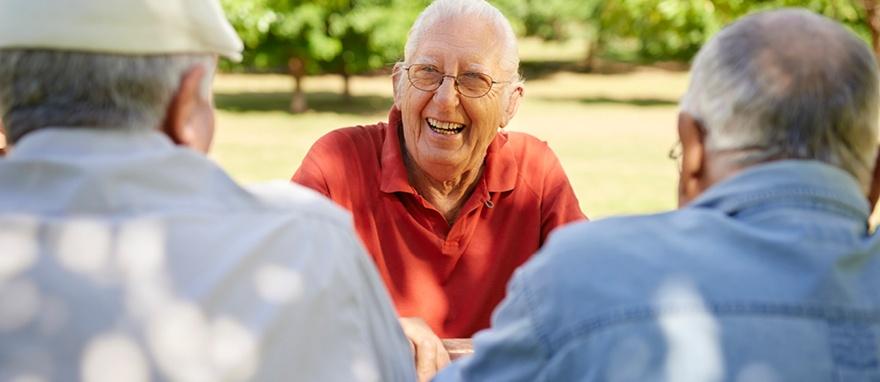 Seniors laughing together at an outdoor table