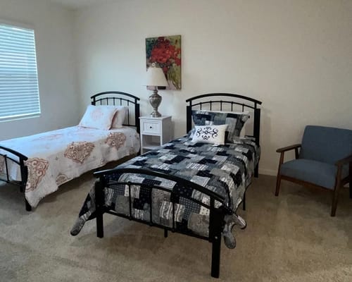 A cozy resident room with two beds and a chair