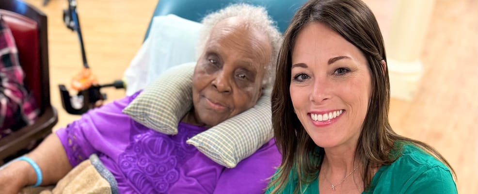 Staff member poses with a resident in a cozy interior setting