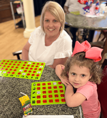 Resident and child playing bingo at a dining table
