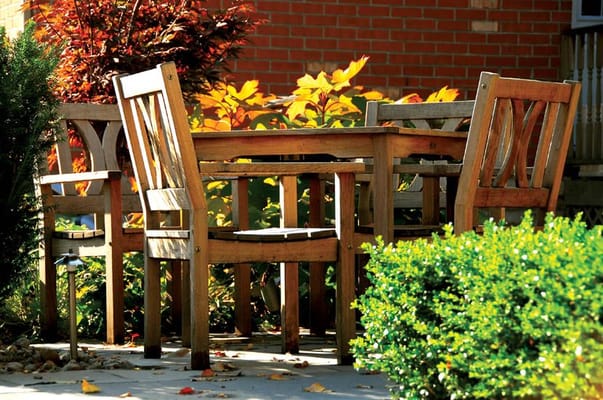 Outdoor seating area with wooden furniture and autumn foliage