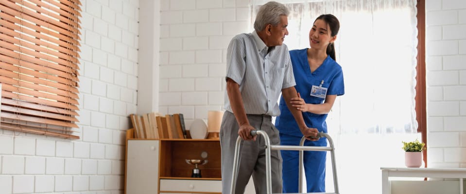 Staff assisting a resident with a walker in a bright room