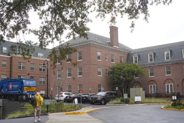 Exterior view of a nursing home with residents and vehicles