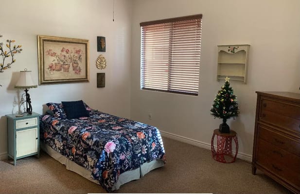 Bedroom with floral bedding, a lamp, and decorative art