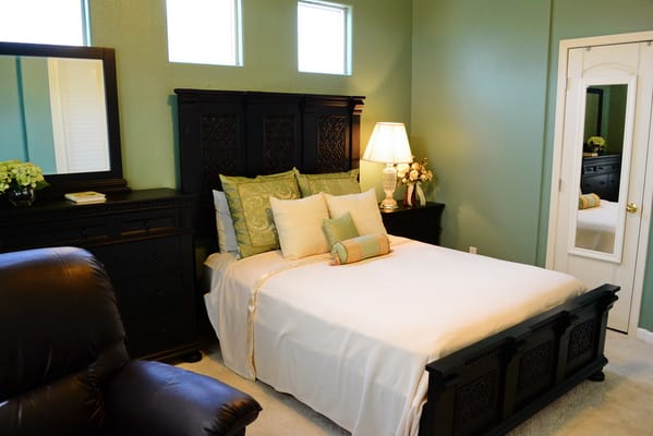 A well-decorated bedroom with a bed, dresser, and lamp