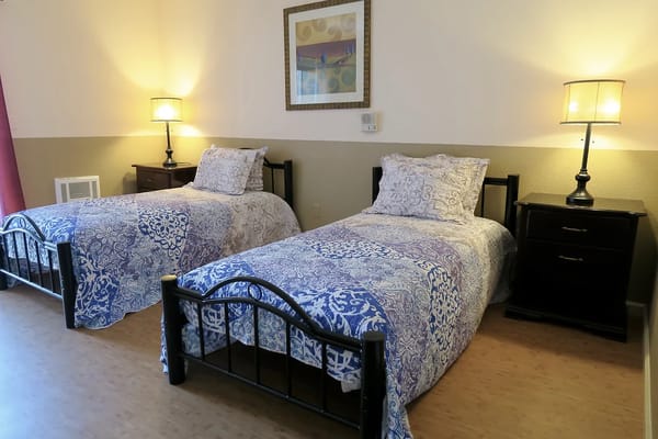 Two twin beds with blue patterned bedding in a shared bedroom